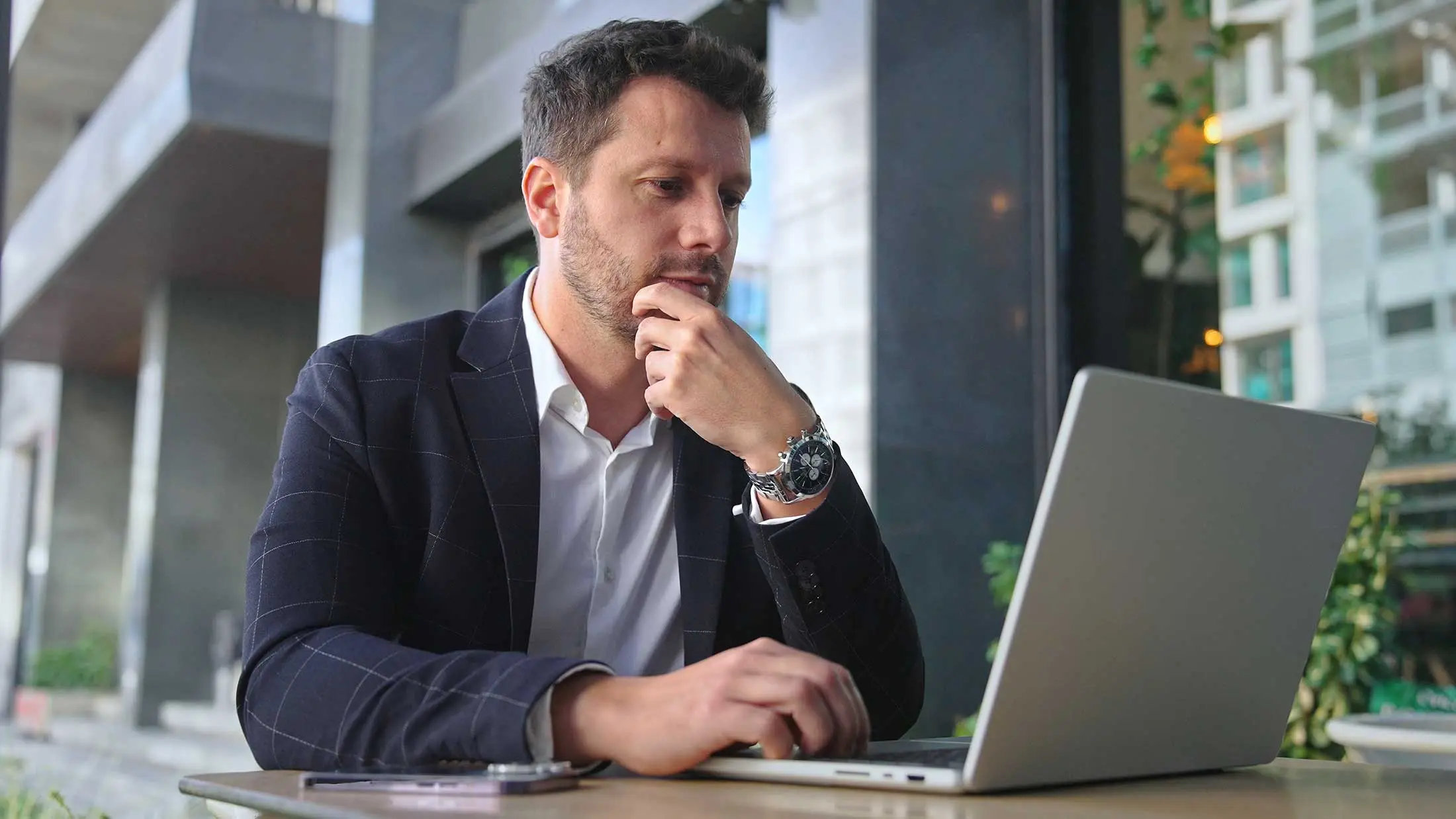 Een man in een pak zit aan een tafel en kijk geconcentreerd naar de SustainQ resultaten op zijn laptop.